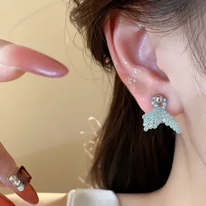 Detailed view of elegant silver needle rice bead fishtail stud earrings worn on ear
