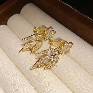 Detail of 14k gold plated clip-on earrings with sparkling zirconia floral leaf design