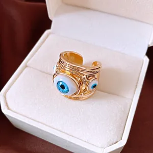 Close-up of a gold-colored evil eye open ring with blue resin details in a gift box.