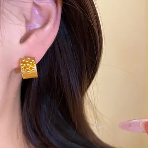 Retro gold C-shaped flower stud earrings with a textured vintage design shown on model