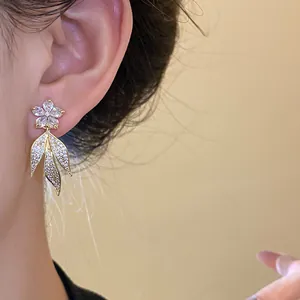 Detailed close-up of 14k gold-plated floral earrings with sparkling cubic zirconia leaves