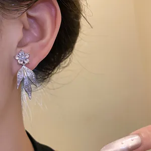 Detailed view of elegant flower and leaf earrings with sparkling zircon inlay