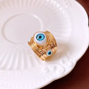 Detail shot of a gold resin evil eye ring on a decorative white ceramic plate