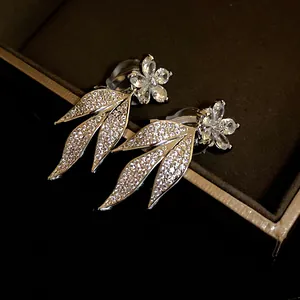 Close-up of sparkling zircon flower and leaf tassel earrings displayed in a dark jewelry box