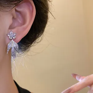 Close-up detail of silver 14k gold plated zircon flower tassel earrings worn on ear