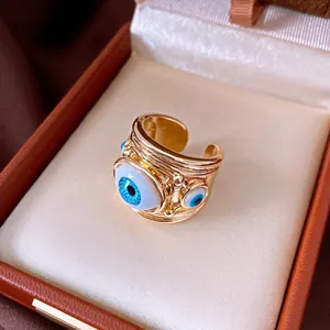 Detail shot of an adjustable gold ring featuring vibrant blue resin evil eye charms