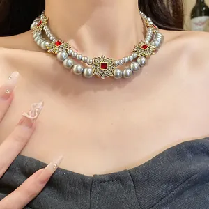 Detail of French vintage double-strand grey pearl necklace with red gems and gold accents