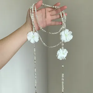 Collana di perle multistrato elegante con fiori di camelia bianchi tenuta in mano