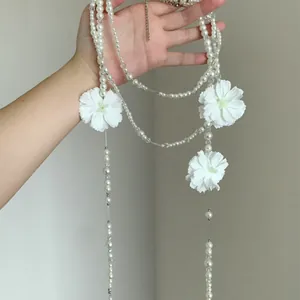 Dettaglio ravvicinato di elegante collana di perle multistrato con fiori di camelia in tessuto