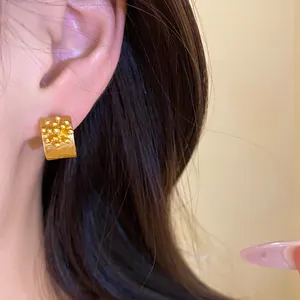 Detailed macro shot of vintage gold C-shaped earrings featuring a floral cluster design.