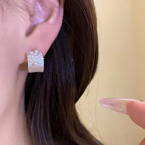 Detailed close-up view of a vintage silver C-shaped stud earring with textured flower pattern