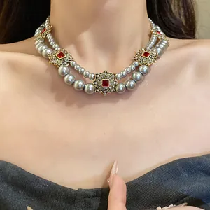 Detail of French vintage double-strand pearl necklace with red gemstone floral accents