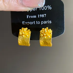 Detailed macro view of vintage gold C-shaped earrings featuring textured floral clusters