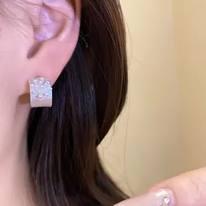 Elegant silver C-shaped flower stud earrings worn by model showing intricate detail