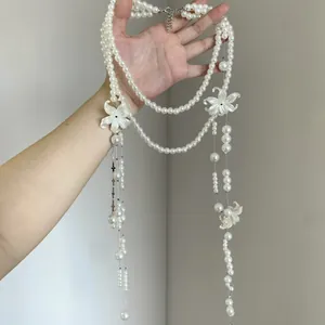 Dettaglio di una collana lunga in perle a più strati con fiori di camelia bianca