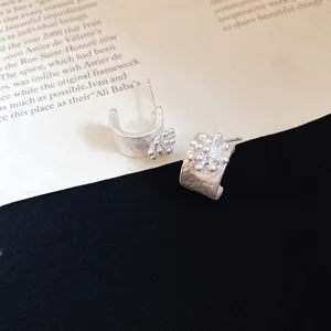 Close-up of vintage silver C-shaped flower stud earrings with a matte textured finish