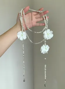 Vista dettagliata di una collana lunga di perle multistrato con accenti di fiori di camelia