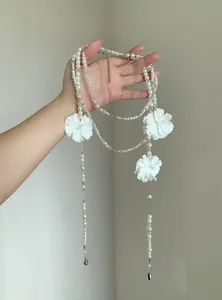 Dettaglio di un'elegante collana lunga di perle multistrato con ciondoli a forma di camelia