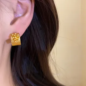 Close-up view of a model wearing retro gold C-shaped earrings with unique floral texture