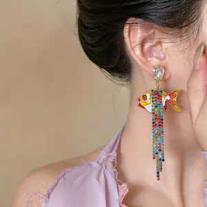 Gros plan de boucles d'oreilles poisson avec glands en strass sur l'oreille d'un modèle