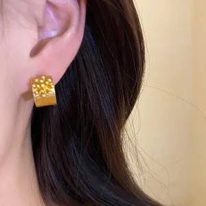 Close-up detail of vintage gold C-shaped stud earrings featuring elegant flower granulation