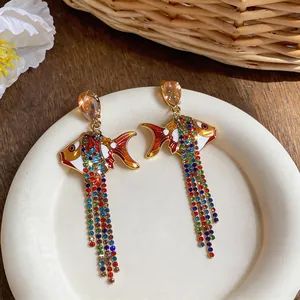 Vue détaillée des boucles d'oreilles poisson en émail avec glands de strass