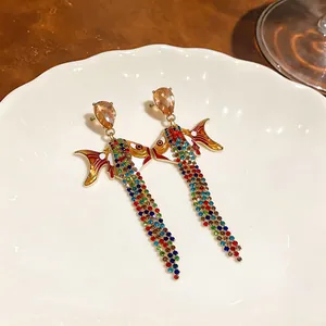 Gros plan de boucles d'oreilles poisson avec glands en strass colorés et émail.