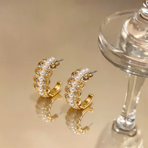 Detailed macro shot of elegant gold C-shaped earrings featuring pearls and small crystals