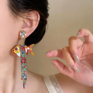Gros plan détaillé d'une boucle d'oreille poisson avec strass colorés portée par un modèle.