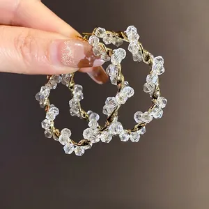 Elegant silver needle twisted hoop earrings decorated with clear faceted crystal beads.