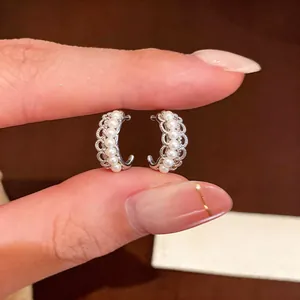 Detailed macro view of silver C-shaped earrings showing intricate lace edges and white pearls