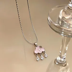 Detailed macro shot of a pink cloud pendant necklace featuring three clear water drop zircons