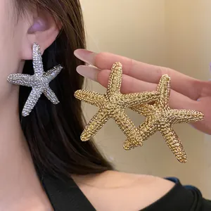 Close-up detail view of elegant textured starfish ear studs in gold and silver finish