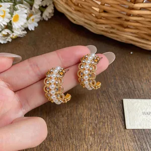 Close-up of vintage gold C-shaped hoop earrings featuring white pearls and crystals