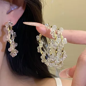 Detailed macro view of elegant twisted gold hoop earrings with clear beaded crystals