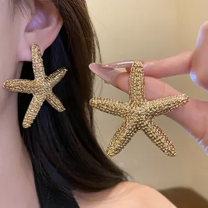 Detailed view of large golden wrinkled starfish stud earrings with a textured surface