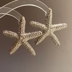 Close-up of textured starfish stud earrings with a detailed wrinkled metallic finish