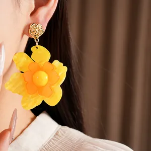 Close-up detail showing the texture of oversized yellow resin flower earring on an Asian model