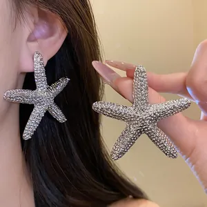 Close-up detail of silver textured starfish stud earrings worn on ear for women