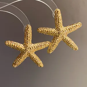 Macro detail of golden textured starfish earrings with a sparkling metallic finish