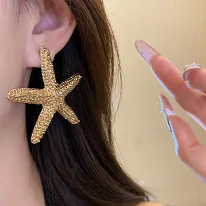 Close-up showing the detailed texture and golden finish of a starfish stud earring