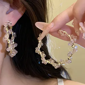 Macro detail of elegant twisted gold hoop earrings wrapped with clear faceted beads.