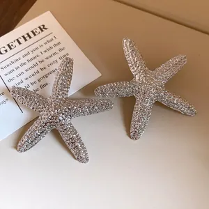Close-up of textured silver starfish stud earrings with a stylish wrinkled surface.