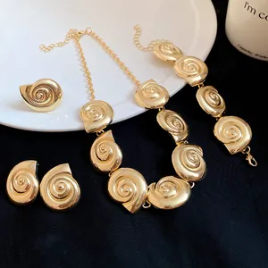 Detail view of retro gold metallic seashell jewelry set on a dark elegant backdrop