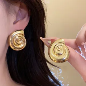 Close-up detail of golden conch shell earrings showing vintage metal texture and elegant wearing effect