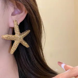 Close-up detail of golden wrinkled starfish stud earring with premium textured finish