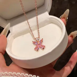 Detailed close-up of elegant rose gold flower necklace with pink zircon in a white gift box.