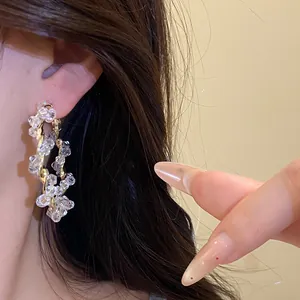 Close-up of elegant gold twisted hoop earrings with clear crystal beads on model