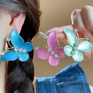 Macro view of colorful butterfly stud earrings with shiny enamel and sparkling rhinestones
