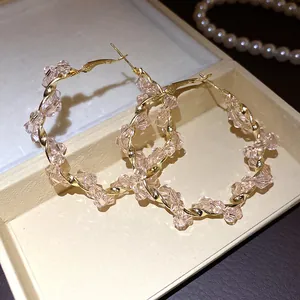 Elegant gold twisted hoop earrings with sparkling pink crystal beads detail